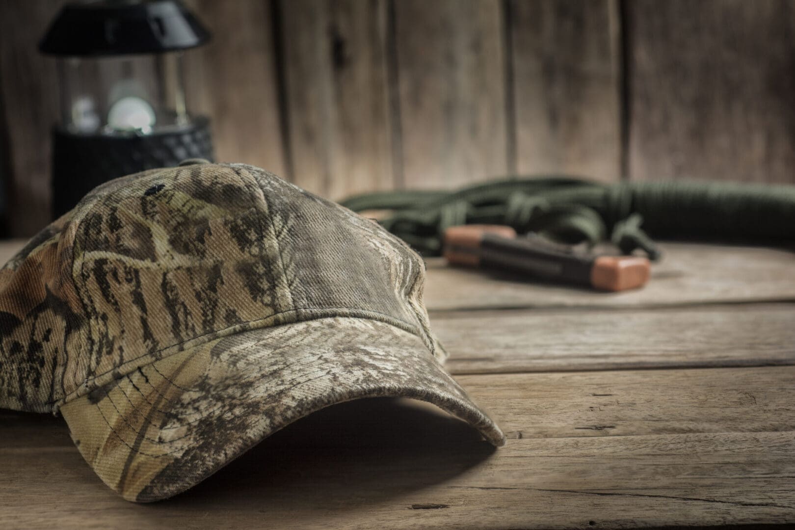 Camo hat on wooden table, rustic background.