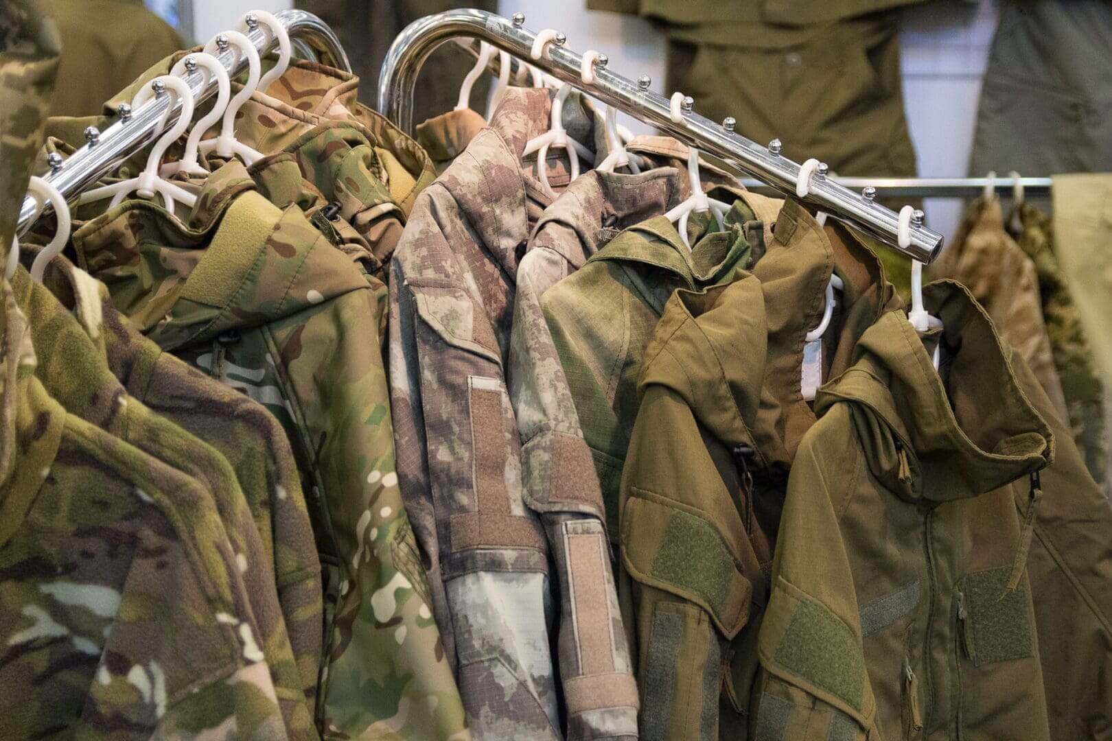 Camouflage jackets hanging on clothing rack.
