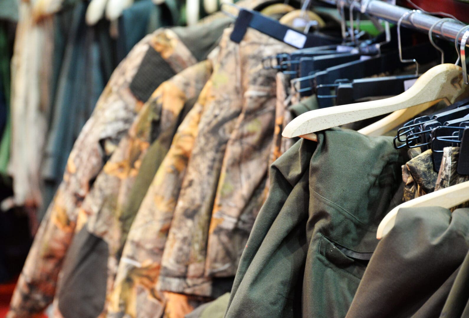 Camouflage and green jackets on hangers.
