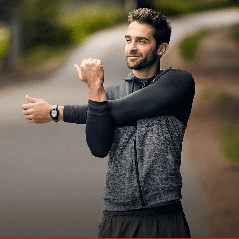 Man stretching outdoors in athletic wear.